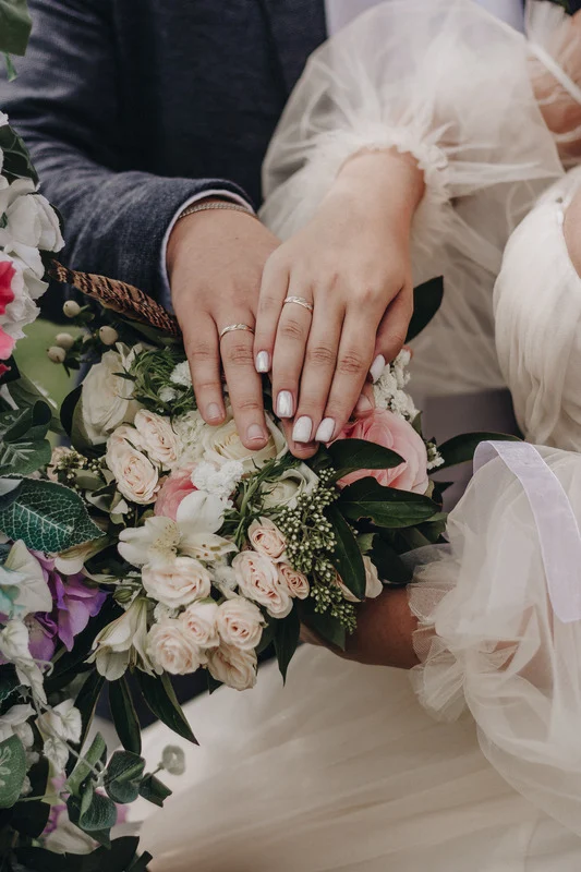 Bride and groom showing new rings over bouquette