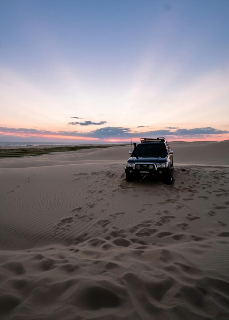 Person driving on a beach in a four-wheel drive vehicle