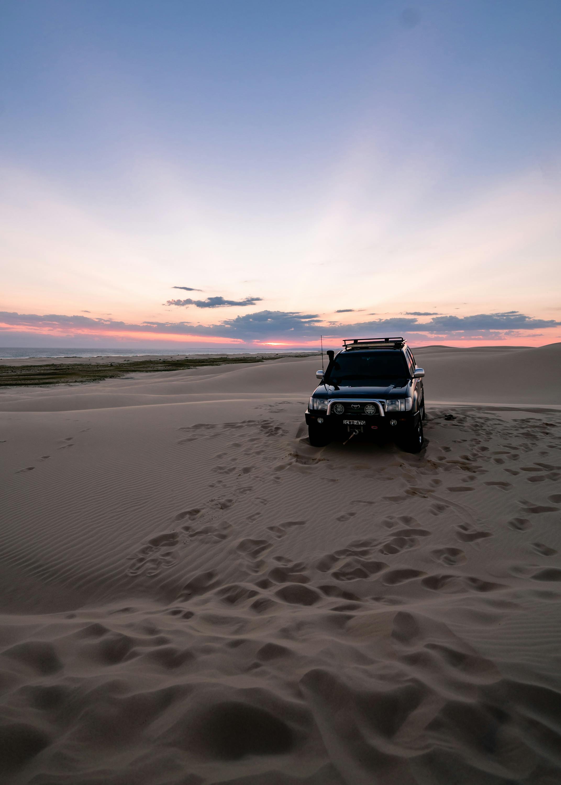 Person driving on a beach in a four-wheel drive vehicle