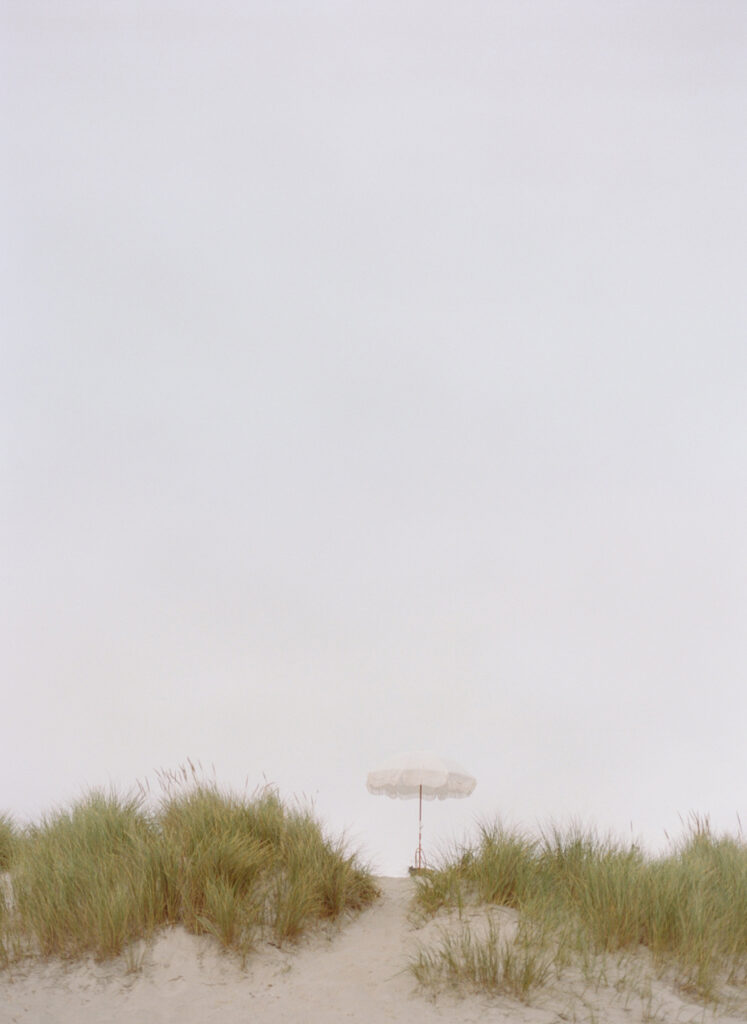 Beach sand dunes with a beach umbrella in the distance